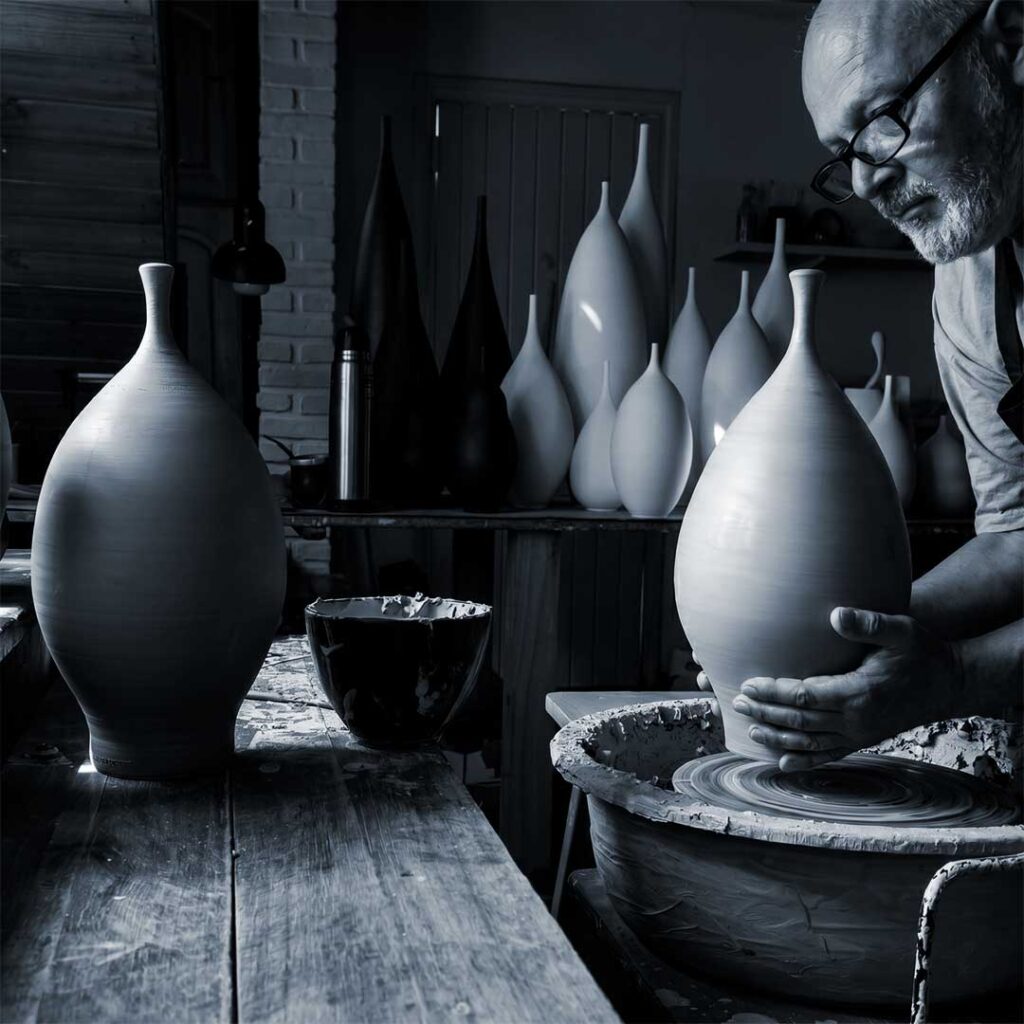 Ceramista artesanal modelando un jarrón de gres en el torno alfarero en su taller.