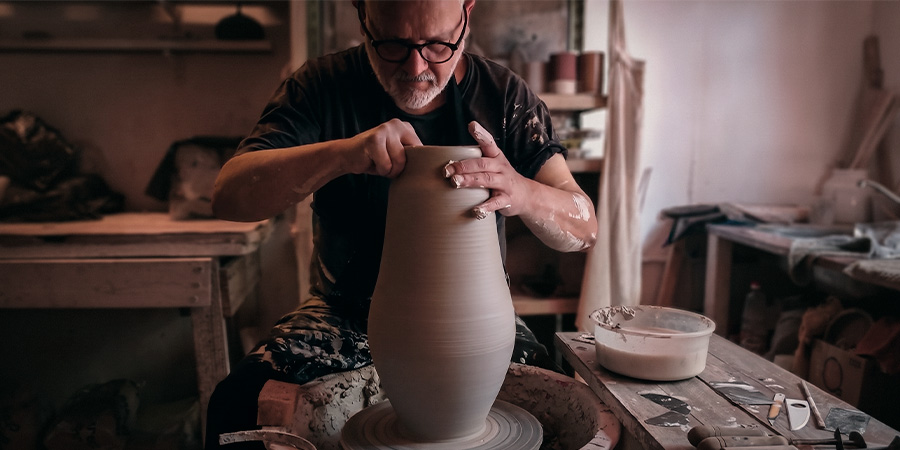 Un maestro ceramista moldeando un jarrón de arcilla en el torno, creando una pieza única de cerámica de autor.