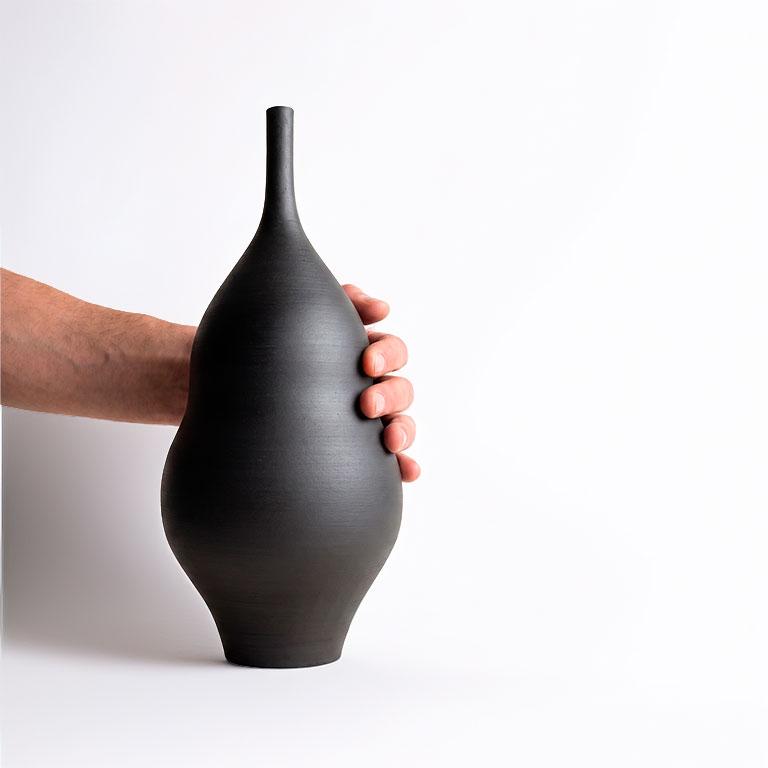 Mano sosteniendo un jarrón de cerámica gres negro mate Unikas Black hecho a mano en torno alfarero